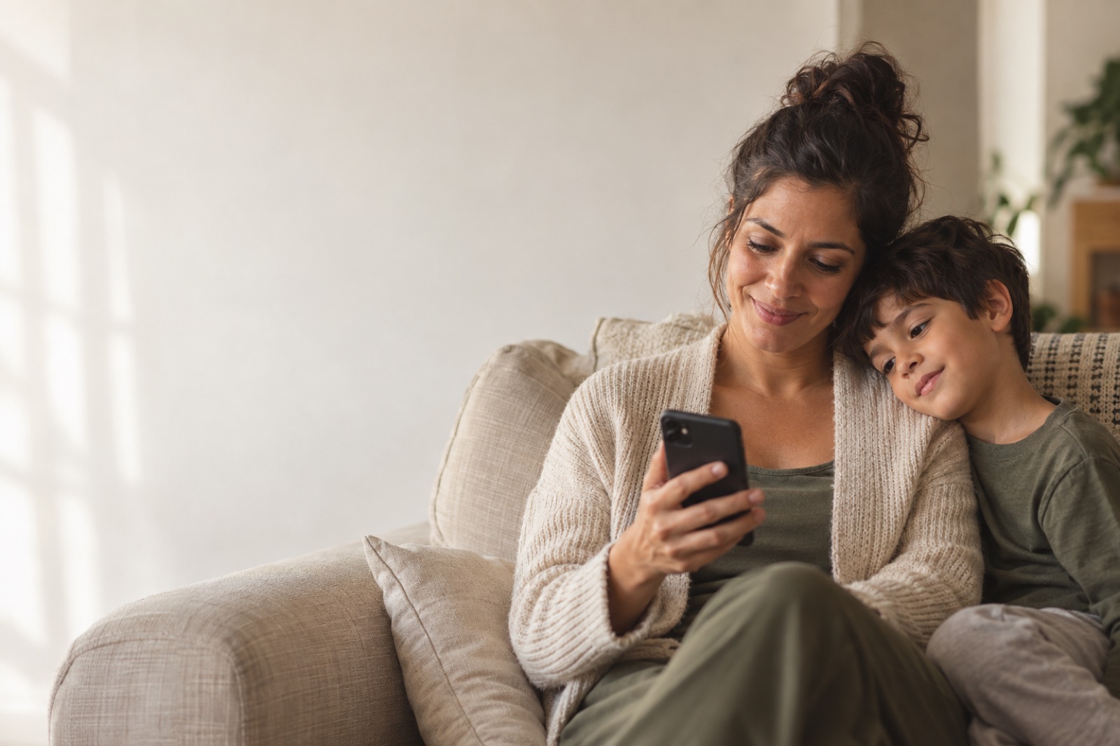 Mãe e filho no sofá, olhando o celular juntos